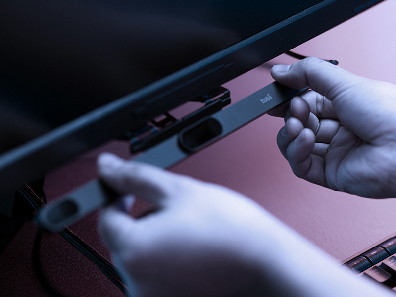 The Tobii Eye Tracker 5 being attached to a computer monitor.